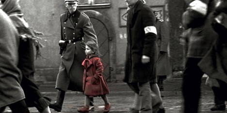 Little girl stands out in a red coat amongst a crowd of black and white soldiers 